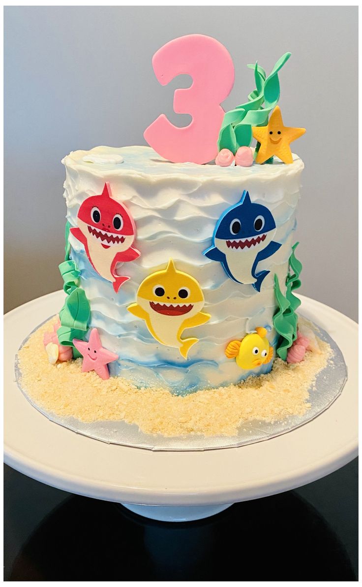 a birthday cake decorated with different types of shark and sea creatures on top of a white plate