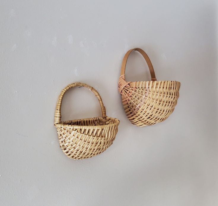 two woven baskets sitting next to each other on a white wall in front of a door