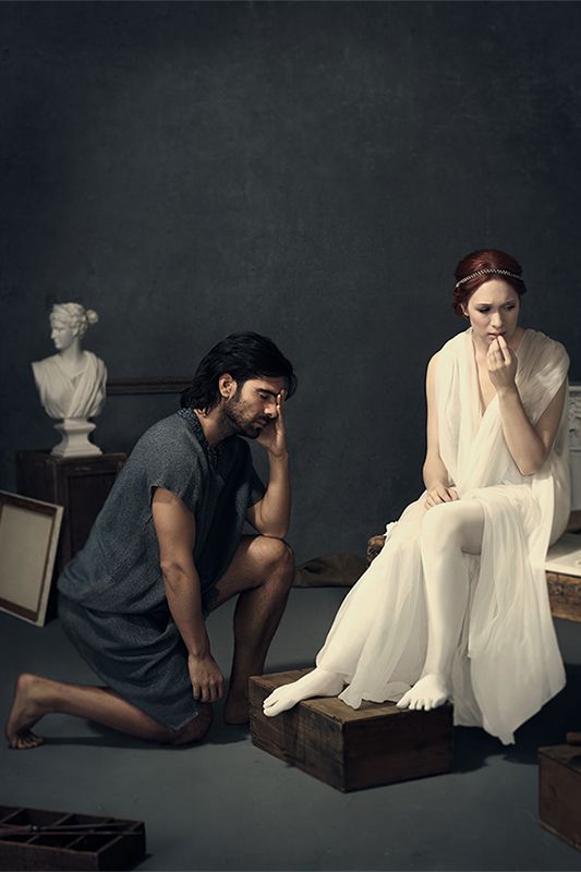 a man kneeling down next to a woman sitting on top of wooden boxes in front of them