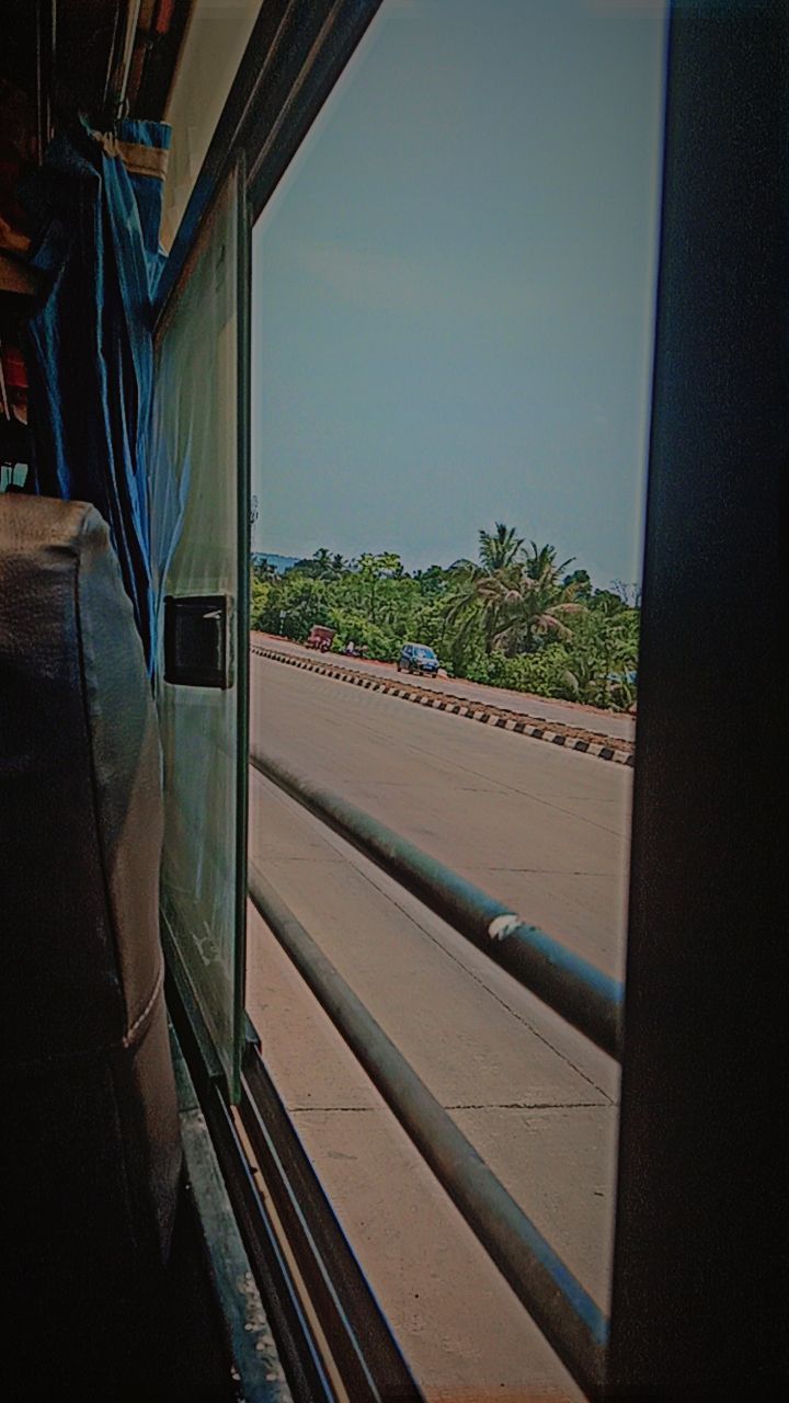 the view from inside a bus looking out at an empty road and palm trees in the distance