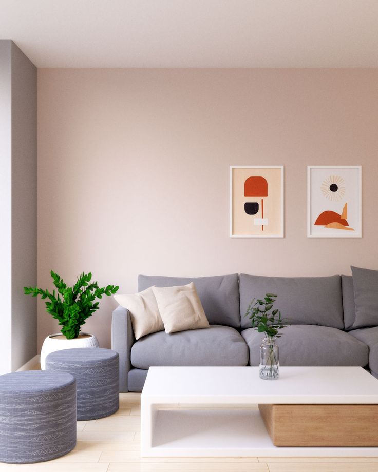 a living room with grey couches and white coffee table in front of pink walls