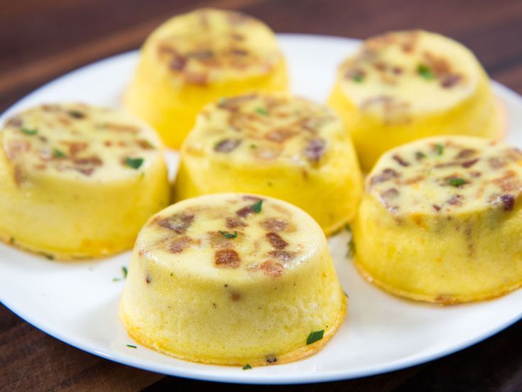 small yellow desserts on a white plate sitting on a wooden table