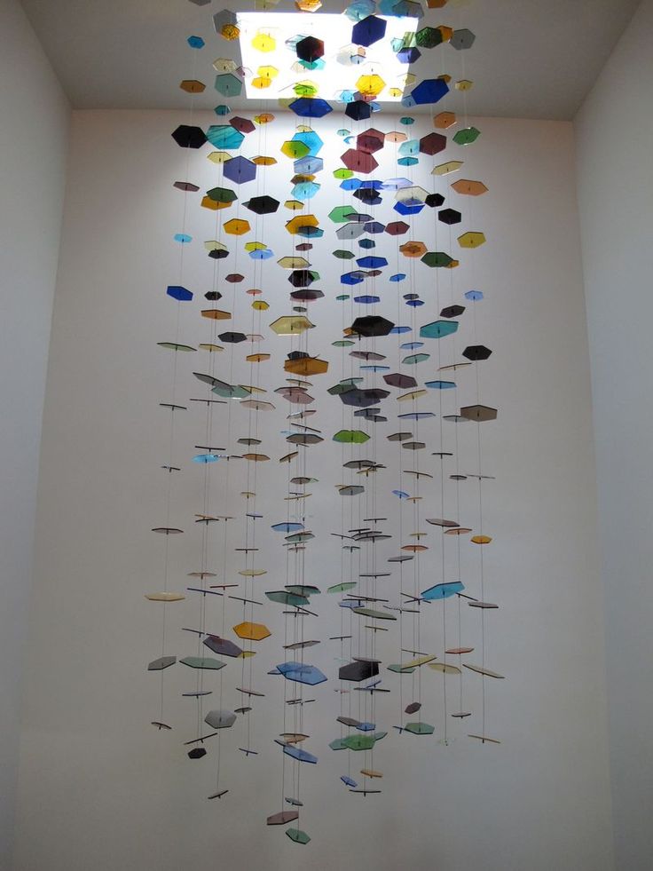 an art installation with many different colored fish hanging from it's sides in a white room