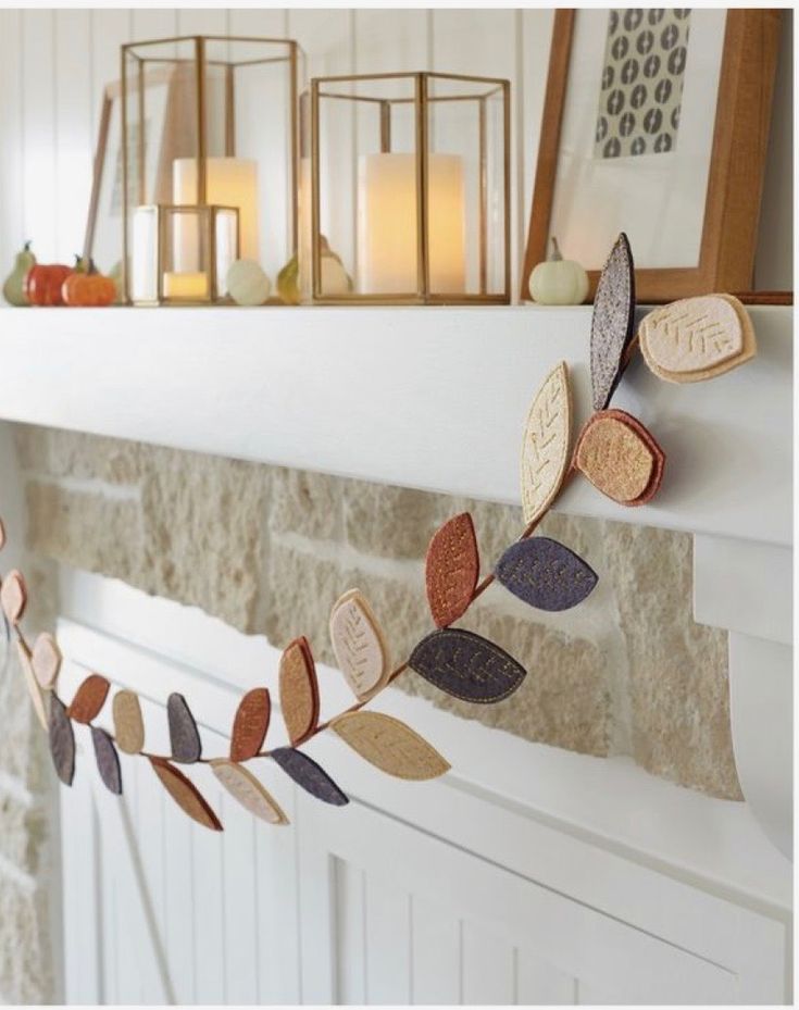 a mantle with candles and leaves hanging from it's sides in front of a fireplace