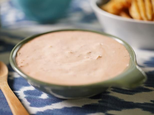 a bowl of dip next to some french fries on a blue and white table cloth