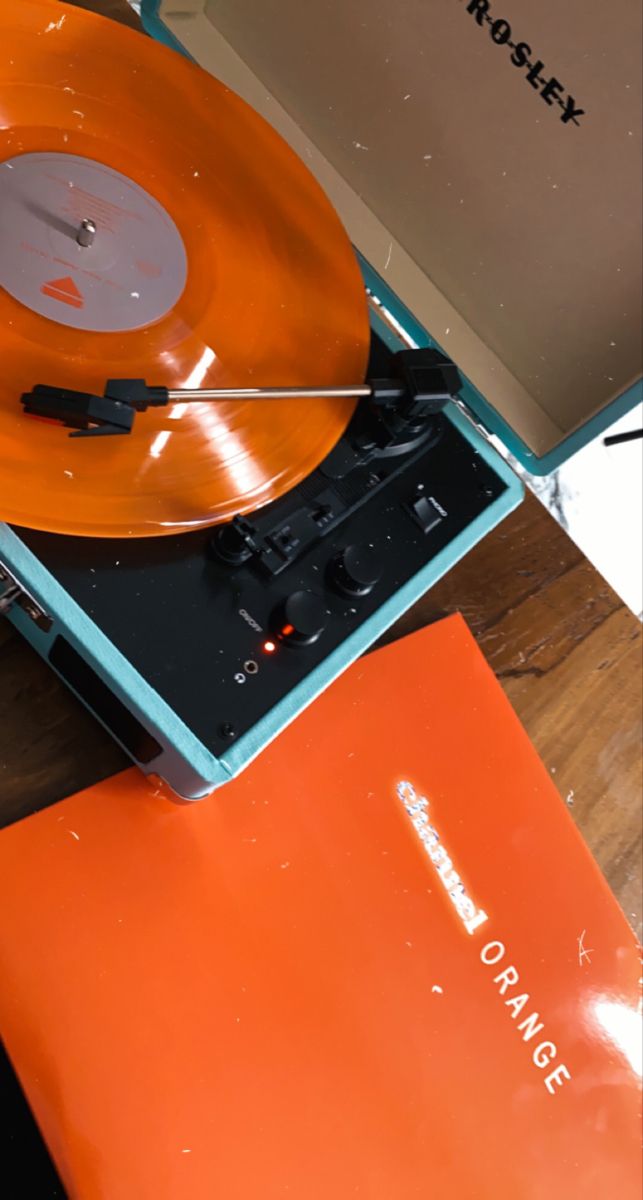 an orange record player sitting on top of a wooden table