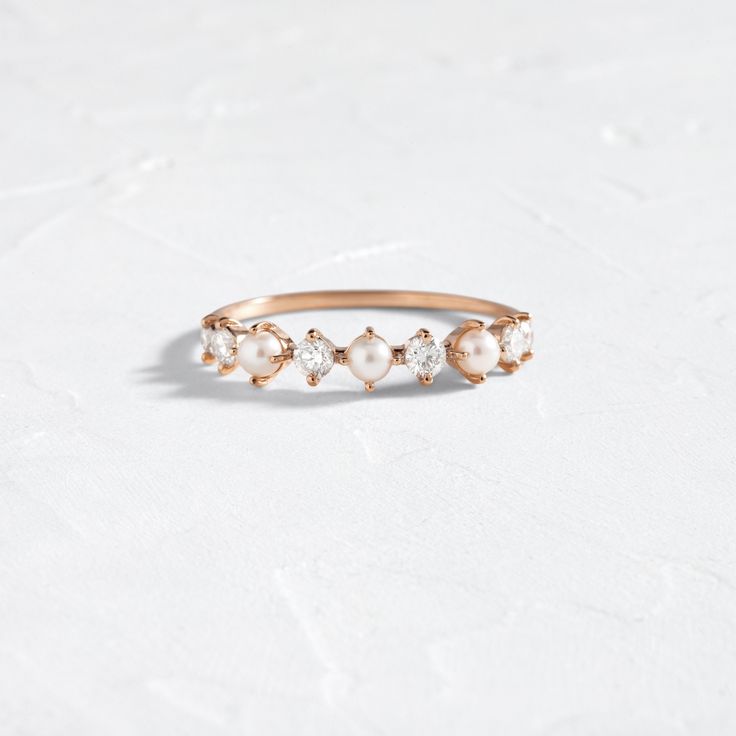 a gold ring with pearls and diamonds on the side, sitting on a white surface