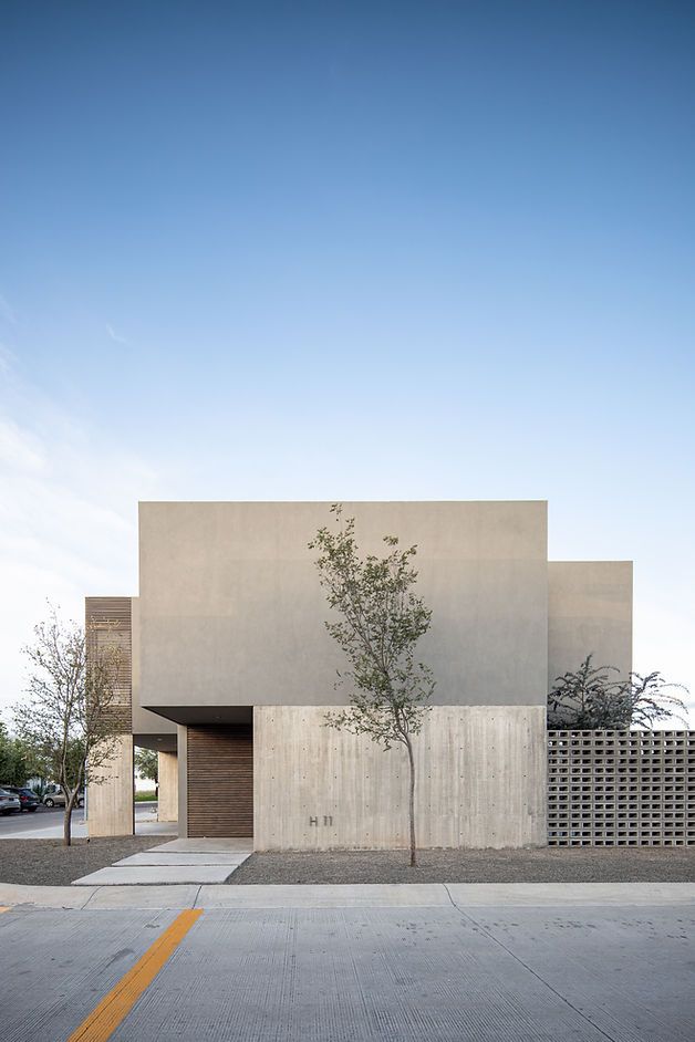 an empty parking lot with a tree in front of a concrete building on the side