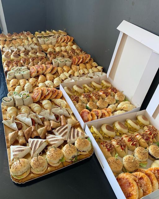 several boxes filled with different types of sandwiches and pastries on top of a table