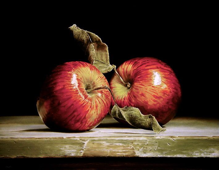 two red apples sitting on top of a wooden table