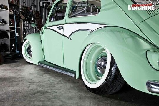 an old green car parked in a garage