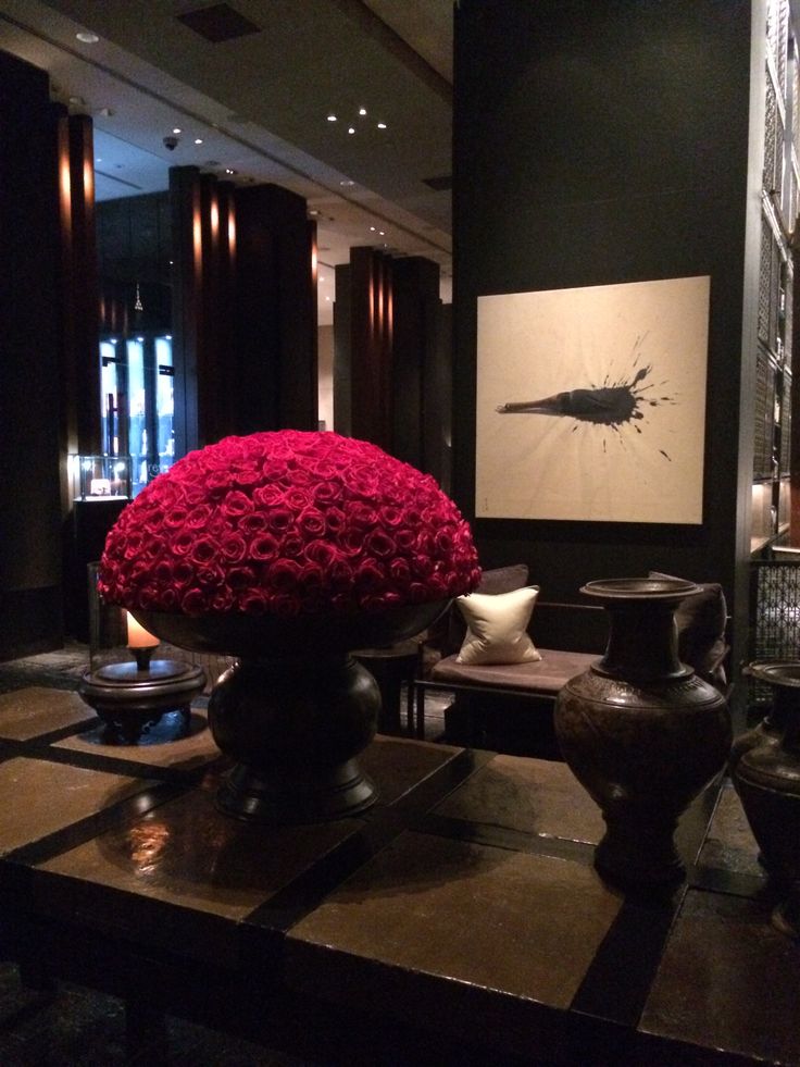 a large vase filled with red flowers sitting on top of a table next to other vases