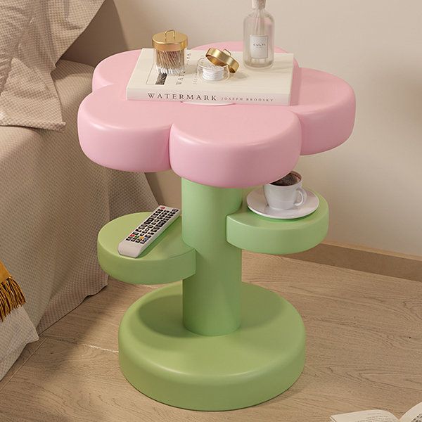 a pink and green table sitting on top of a wooden floor next to a bed