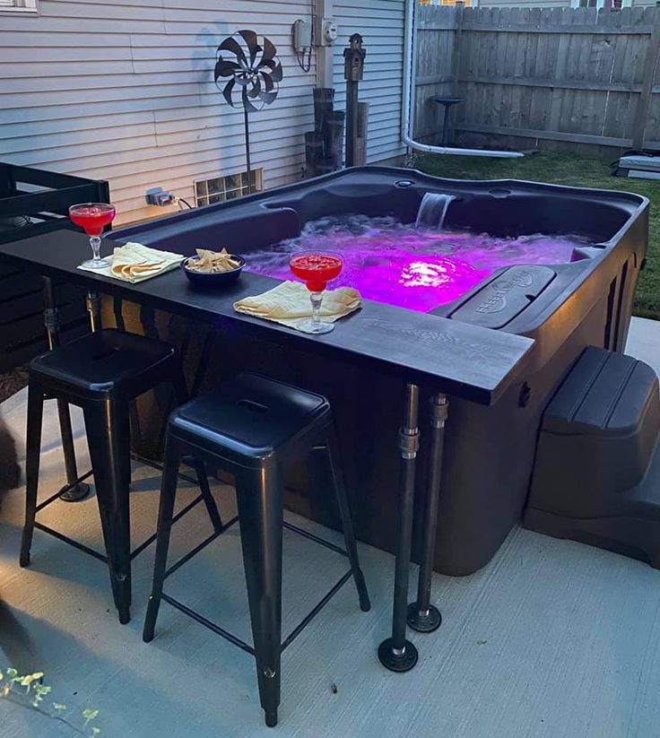 a hot tub sitting on top of a patio next to a table with two drinks