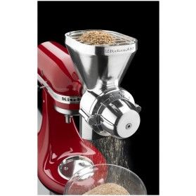 a red mixer sitting on top of a counter next to a bowl filled with grain