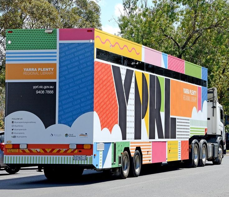 a colorful bus is parked on the side of the road with trees in the background