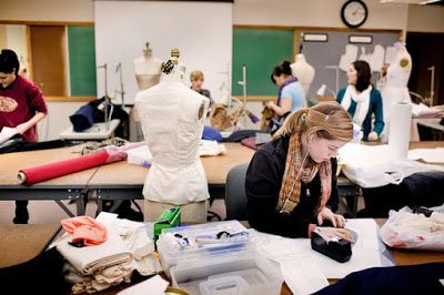 a woman sitting at a table working on some sewing projects with other mannequins in the background