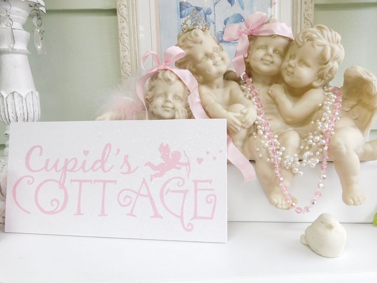 three little cherubs sitting next to a sign that says cupid's cottage