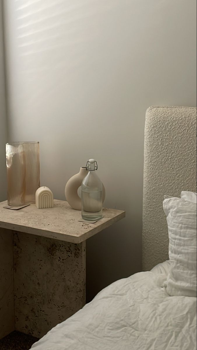 a bed with white sheets and pillows next to a lamp on top of a table