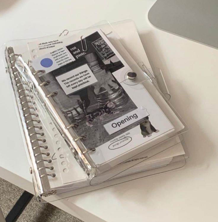 three clear binders sitting on top of a white desk next to a computer keyboard