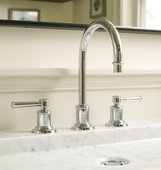 a bathroom sink with two faucets and a marble counter top in front of a mirror