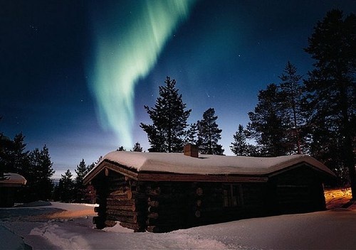 the aurora bore is visible in the sky above a cabin