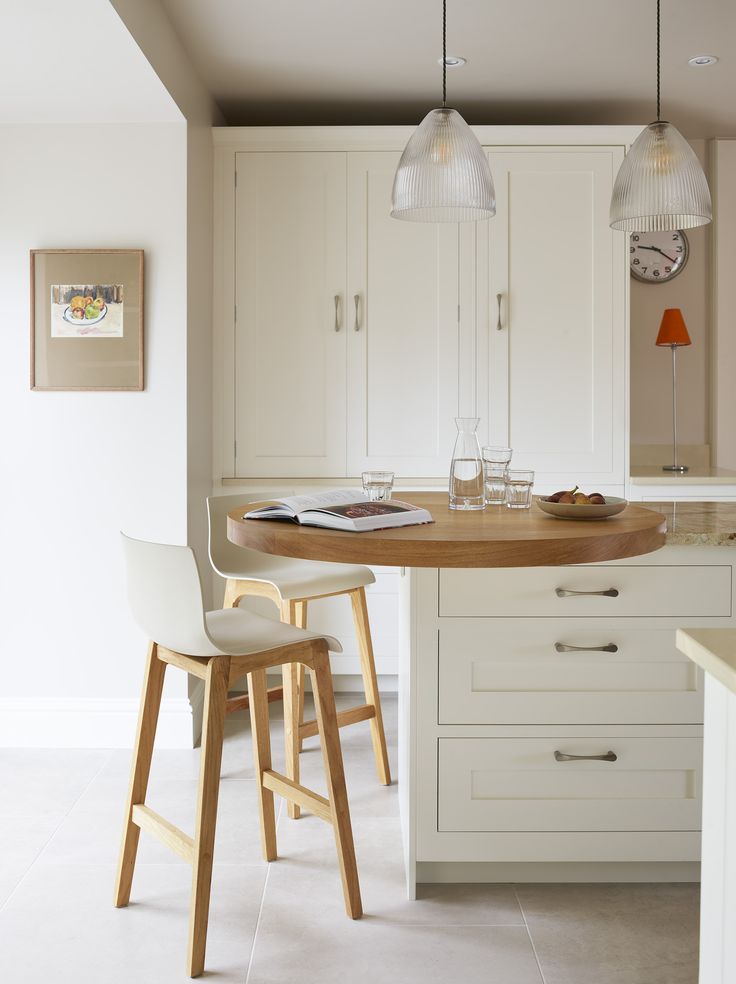 a kitchen with two stools and a table in the middle, next to some cabinets