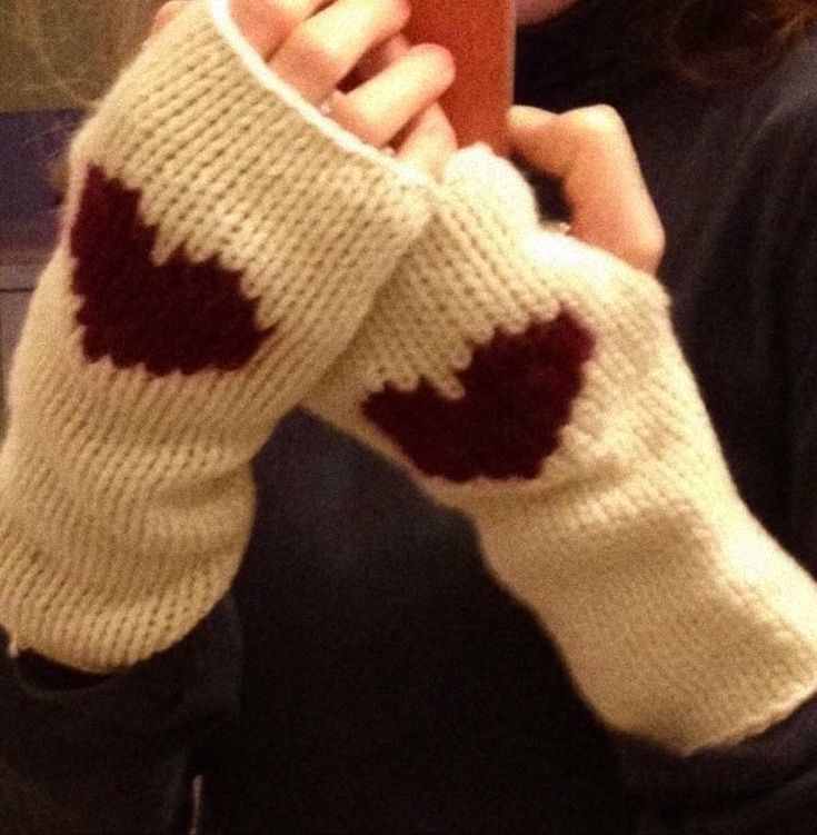 a woman is taking a selfie with her cell phone wearing knitted mitts