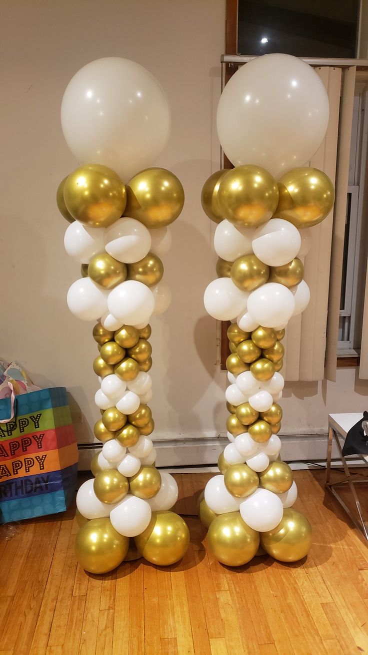 two tall gold and white balloons are on the floor