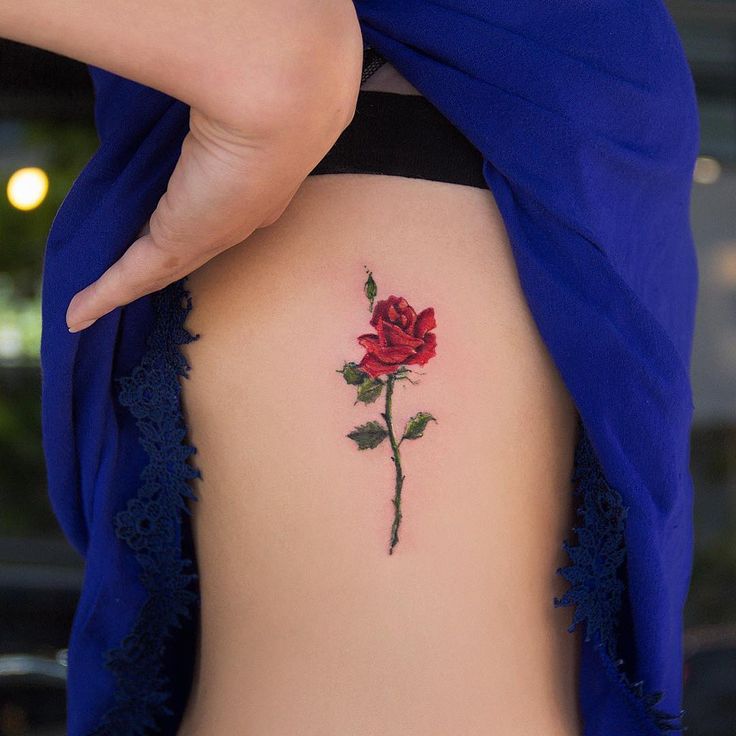 a rose tattoo on the back of a woman's ribcage is shown