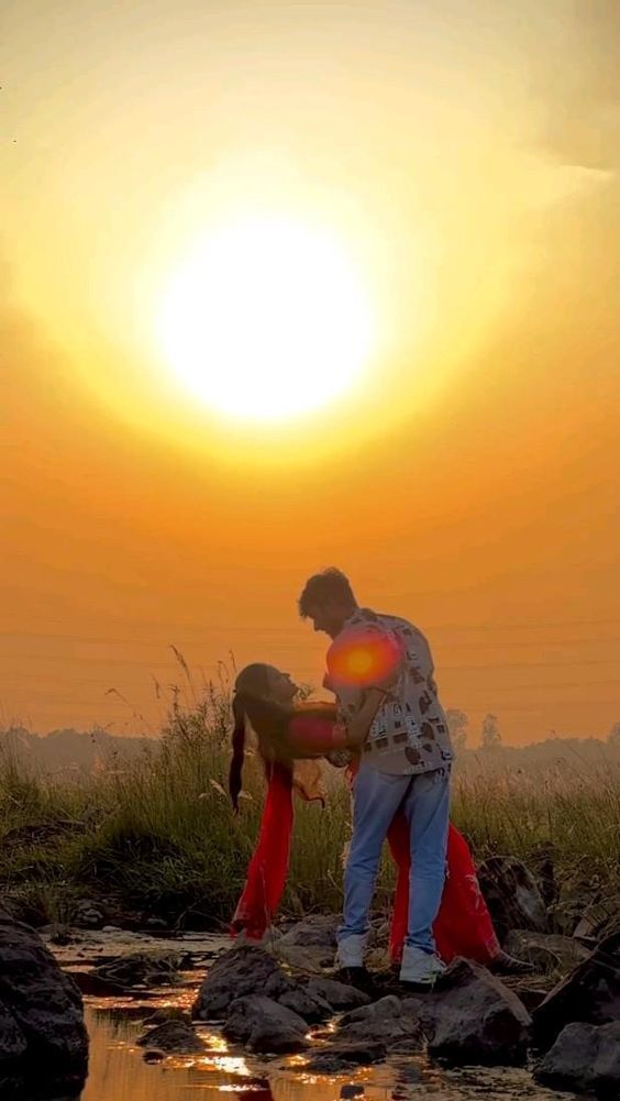 a man standing on top of a rock next to a river under a yellow sun