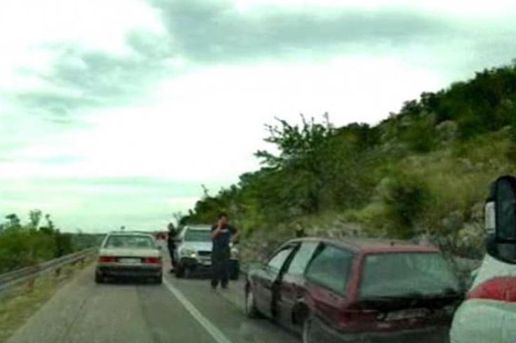 two people standing on the side of a road next to cars