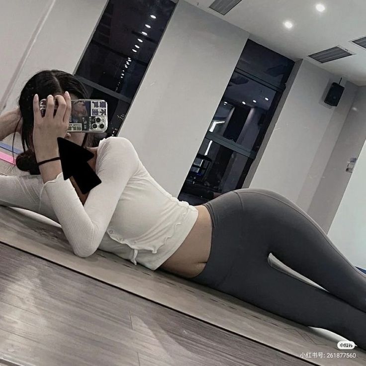 a woman laying on the floor with her cell phone up to her ear and taking a selfie