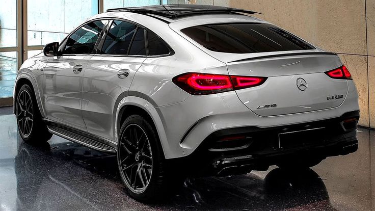 the rear end of a white mercedes suv in a showroom with large glass windows