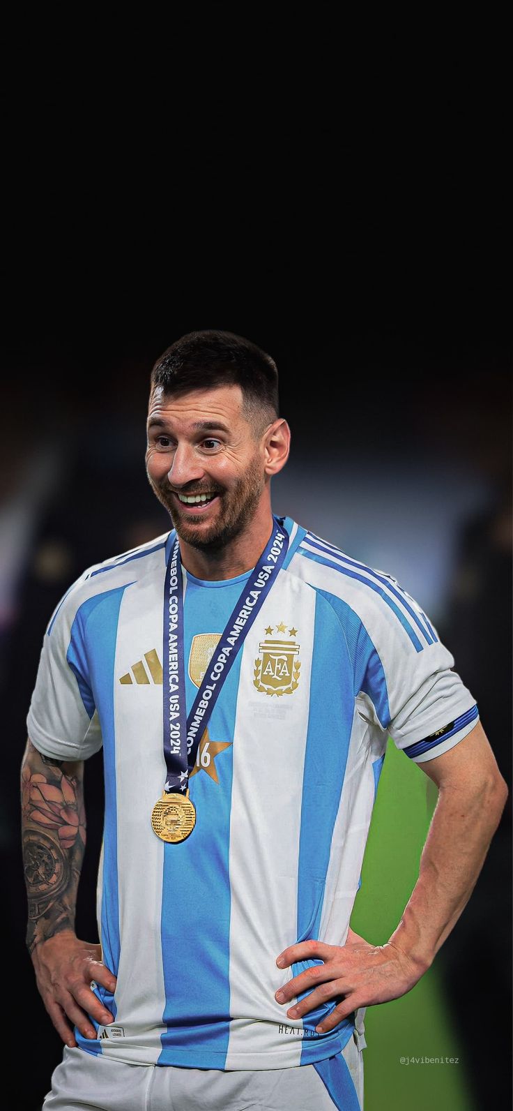 a man with a medal standing in front of a black background wearing a blue and white striped shirt