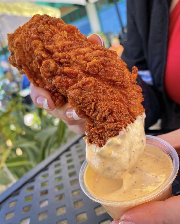 a person holding food in their hand and dipping sauce