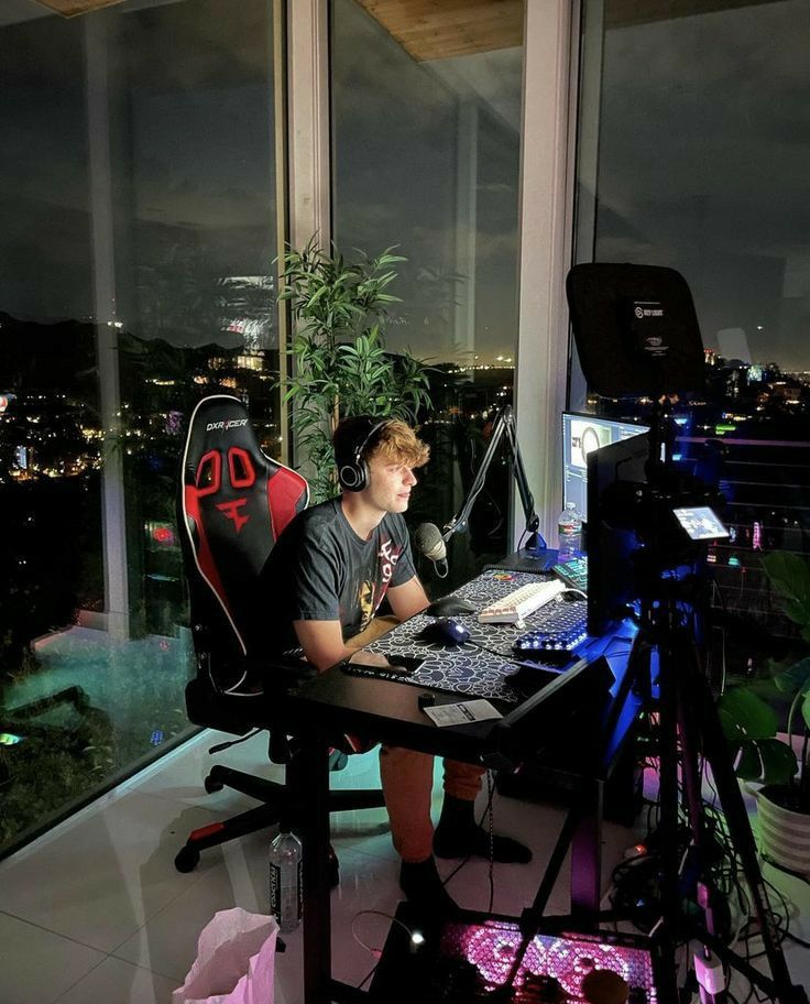 a man sitting at a desk with headphones on in front of a large window