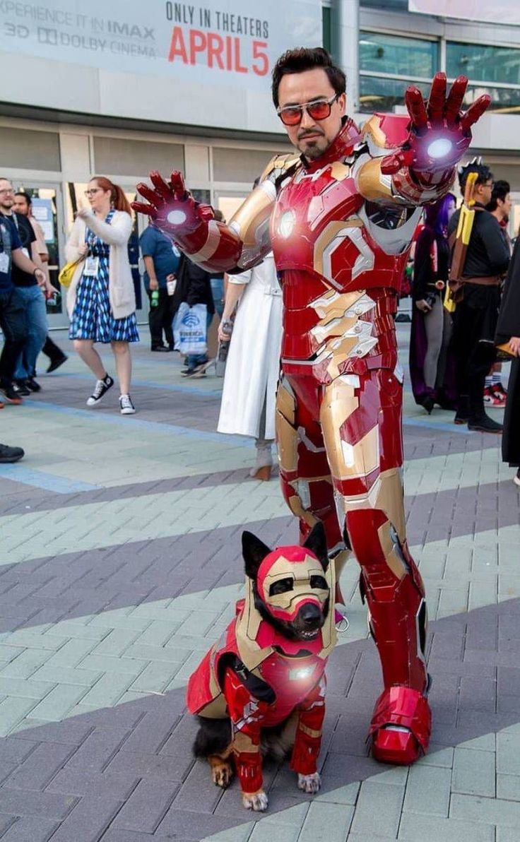 a man dressed as iron man standing next to a dog