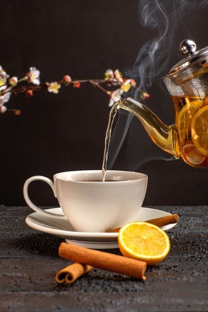 tea being poured into a white cup with orange slices and cinnamons on the side