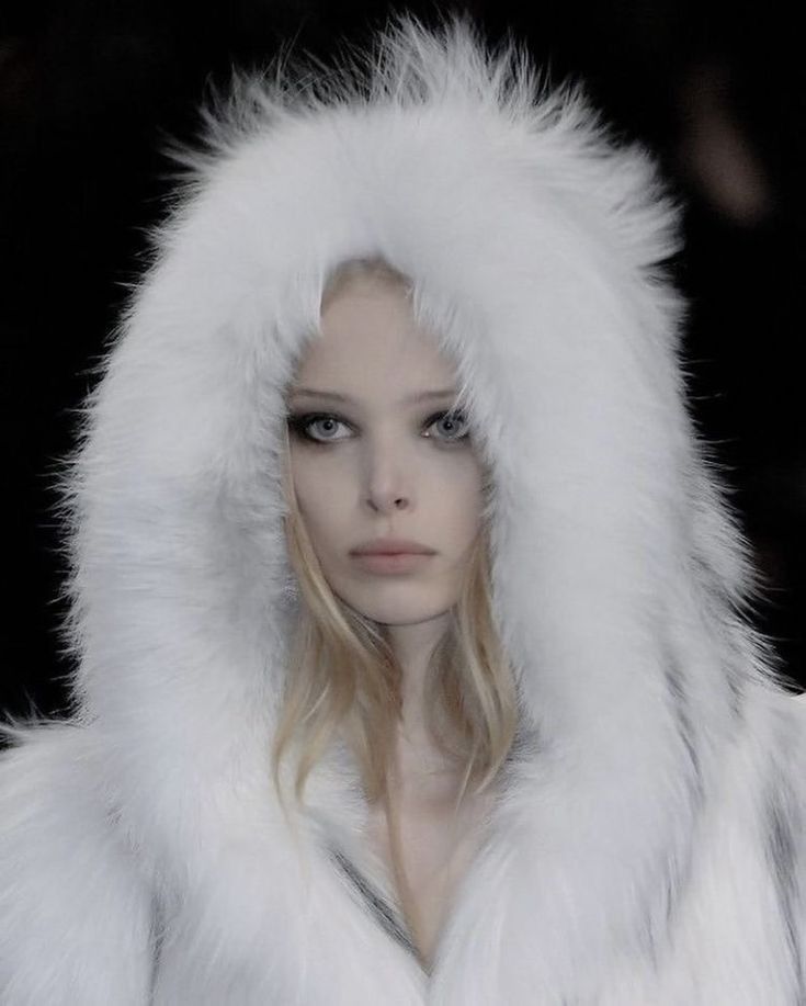 a woman with long hair wearing a white fur coat