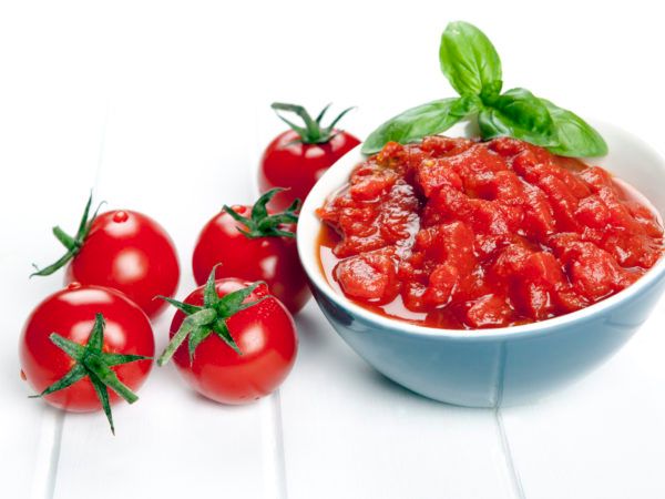 tomatoes and sauce in a bowl with basil on the side, next to some cherry tomatoes