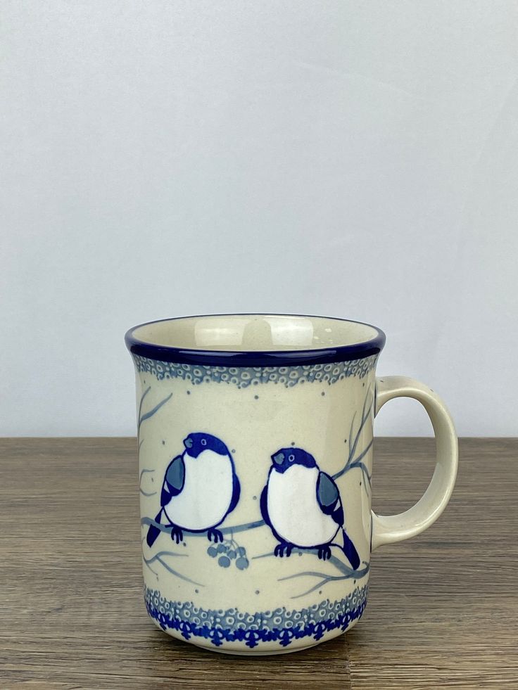 two birds sitting on a branch in a blue and white coffee cup with matching rim