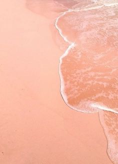 the beach is pink and white with waves coming in