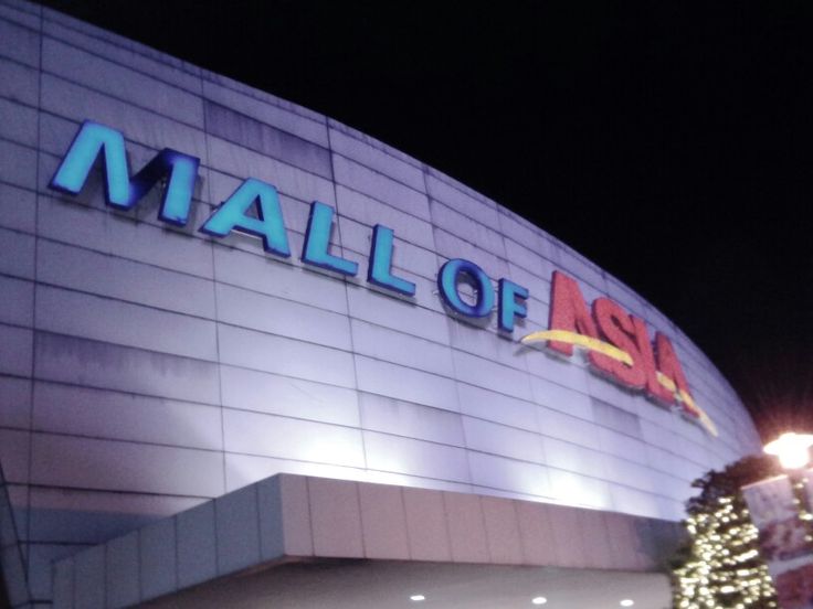 a large building with a christmas tree in front of it and lights on the side