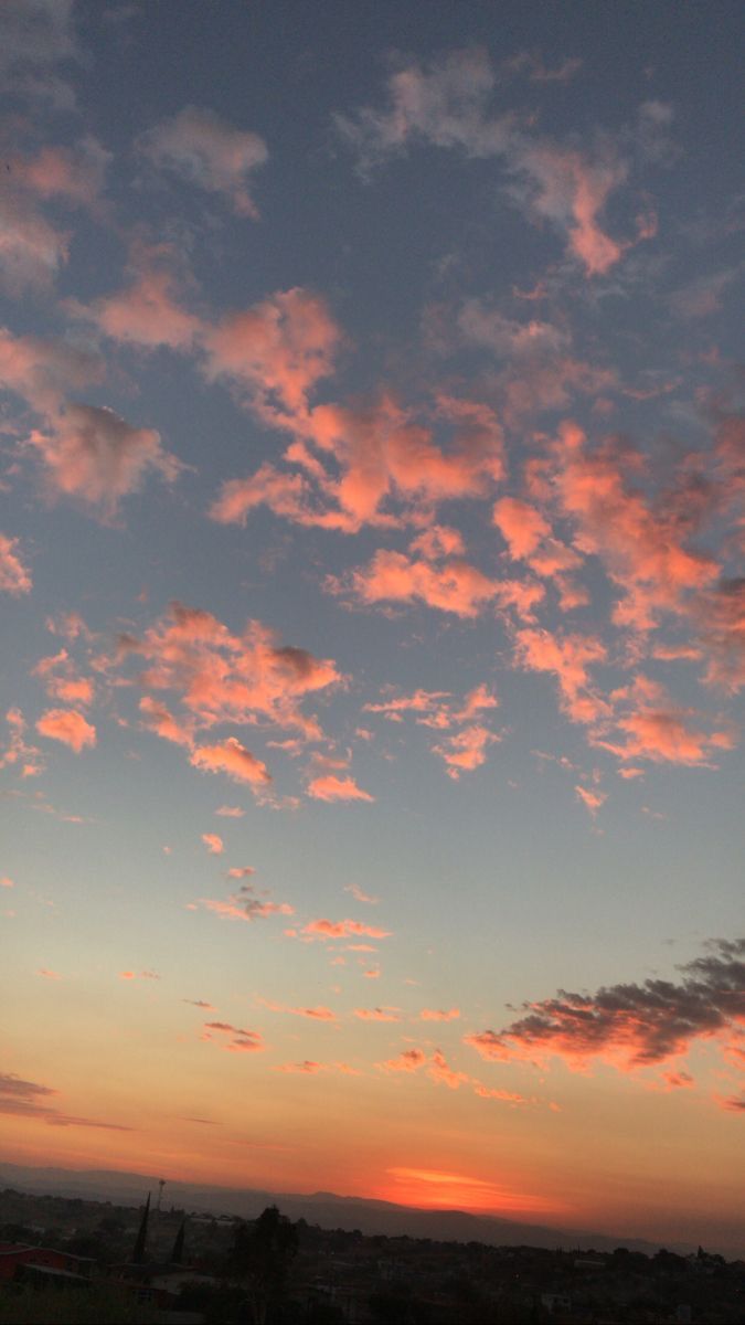 the sky is filled with pink clouds as the sun sets