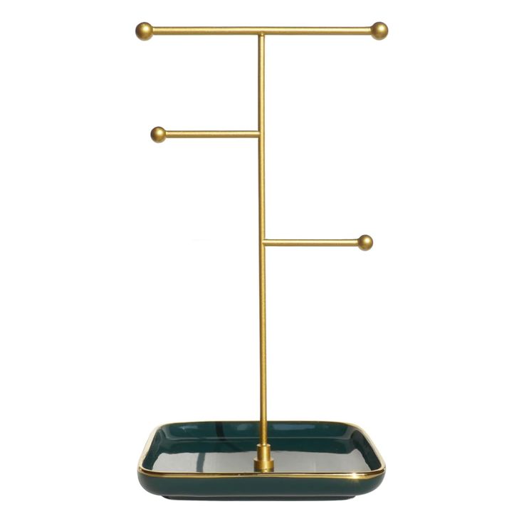 a gold and green tray with two hooks on it, one is holding a cup