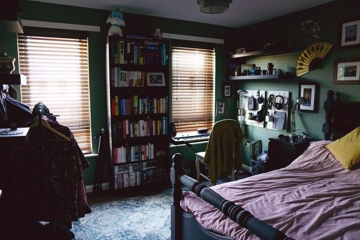 a bedroom with green walls and lots of bookshelves