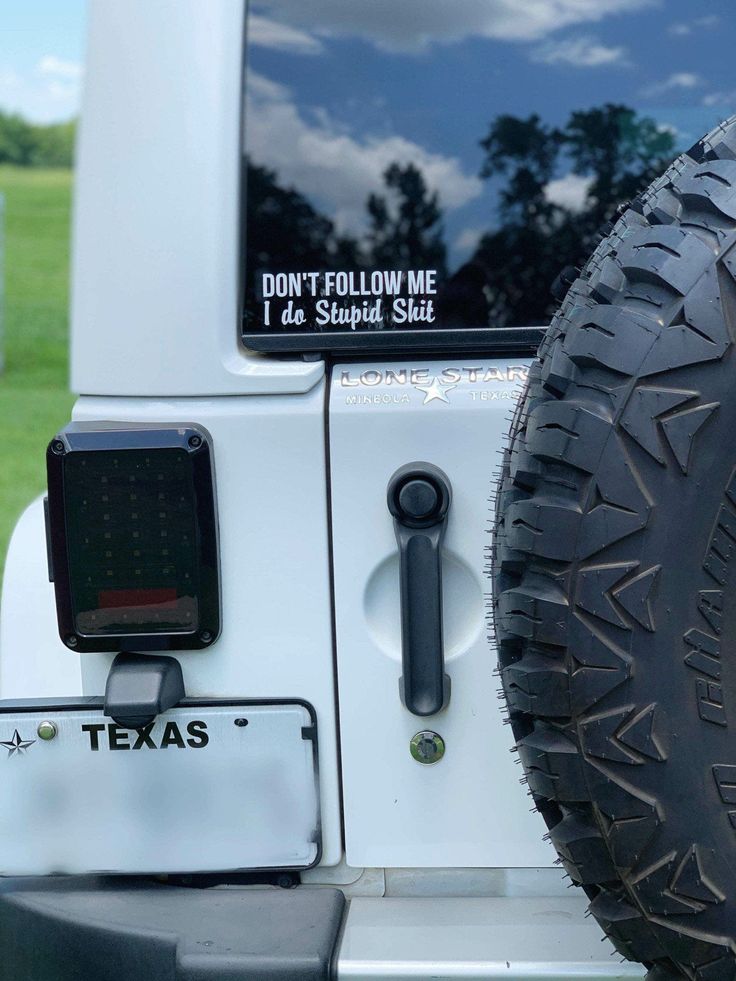 the front end of a white jeep parked in a field