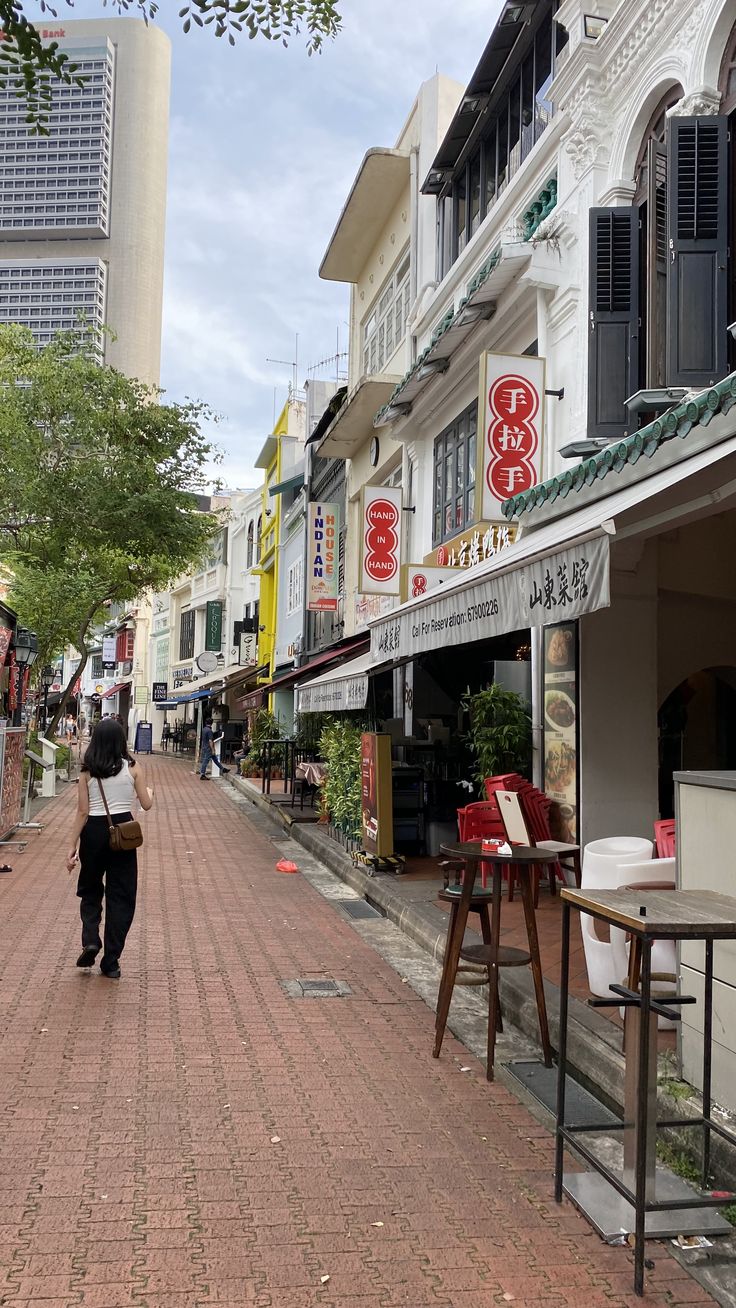 a woman is walking down the street in front of shops