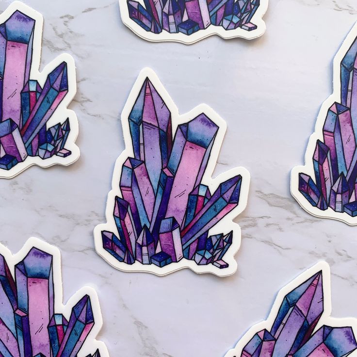 purple and blue stickers on a white marble surface with pink crystals in the middle